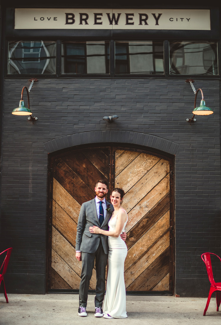 Portrait of bride and groom in front of Love City Brewing taken by Philadelphia wedding photographer