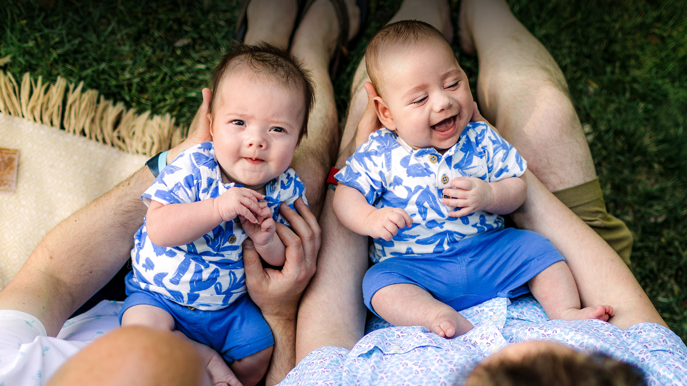twin baby boys in matching outfits laying on dads laps
