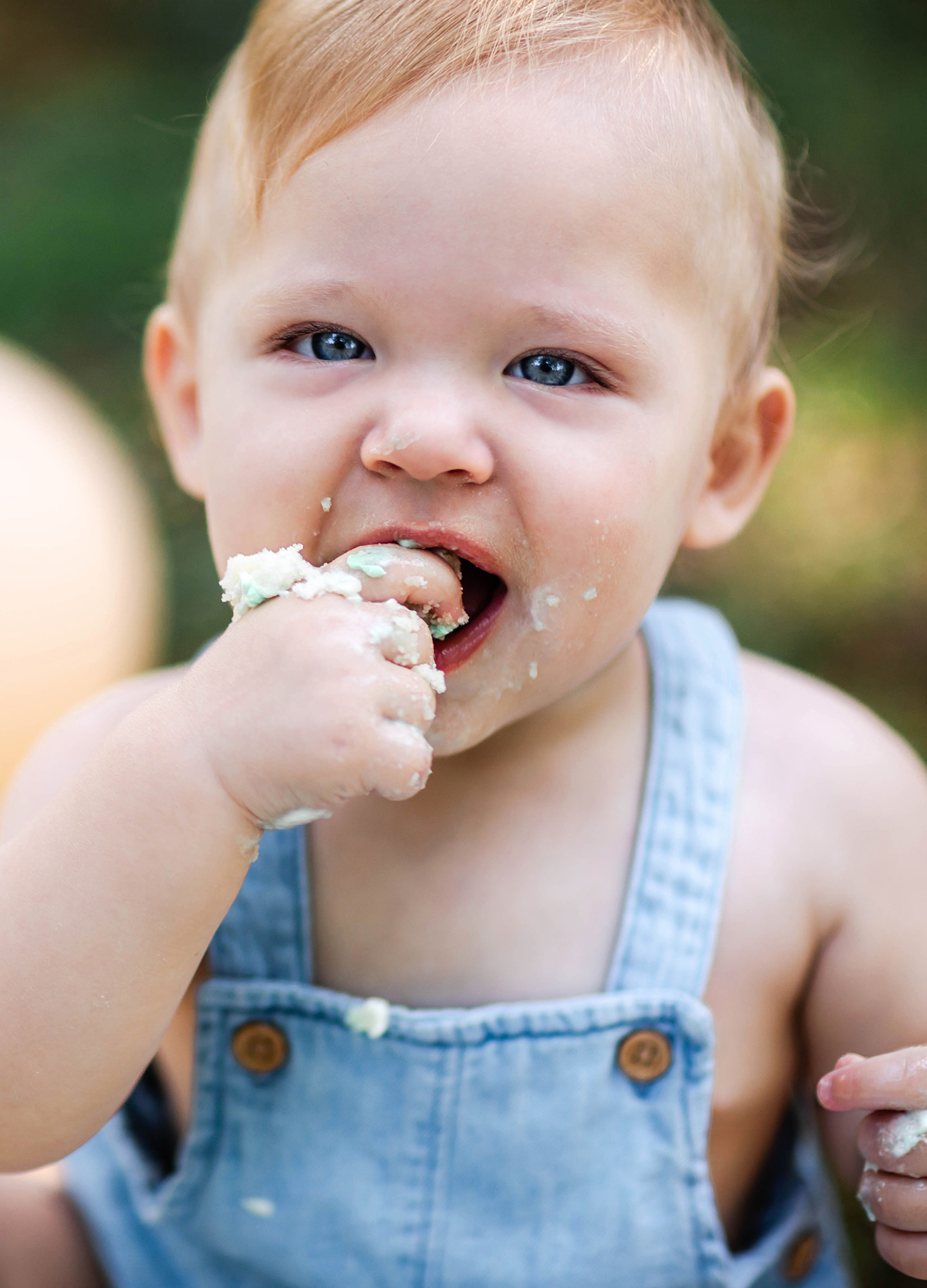 baby bringing cake into his mouth