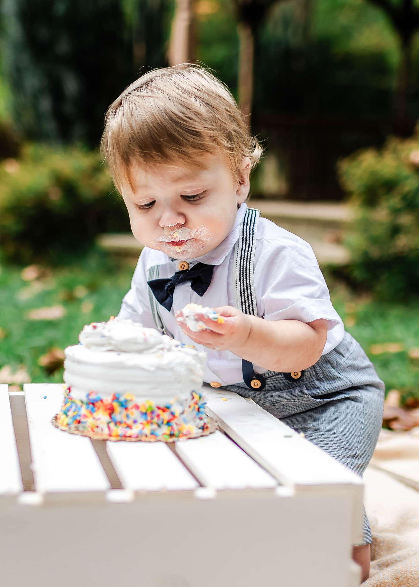 baby looking at his cake covered hand