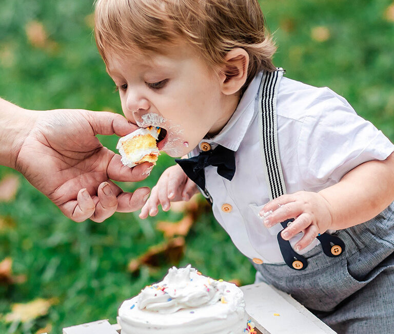 Baby being fed cake during a 1st birthday photoshoot