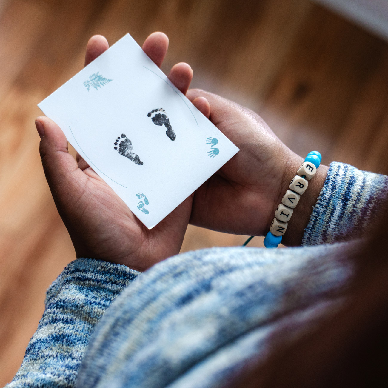 mother's hands holding a card showing tiny baby footprints
