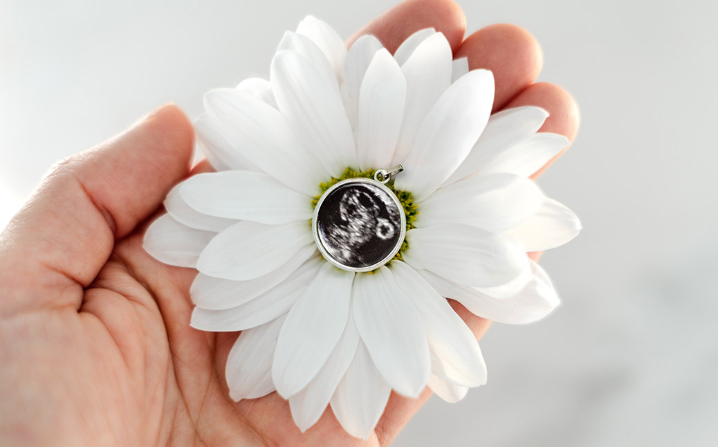 pendant with small fetus ultrasound photo laying inside of a flower
