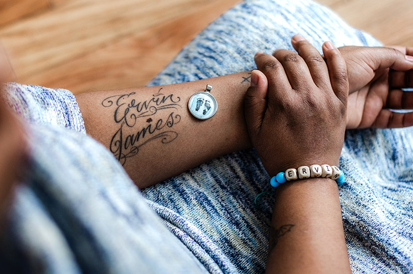 closeup of tattoo of a baby's name and their footprints