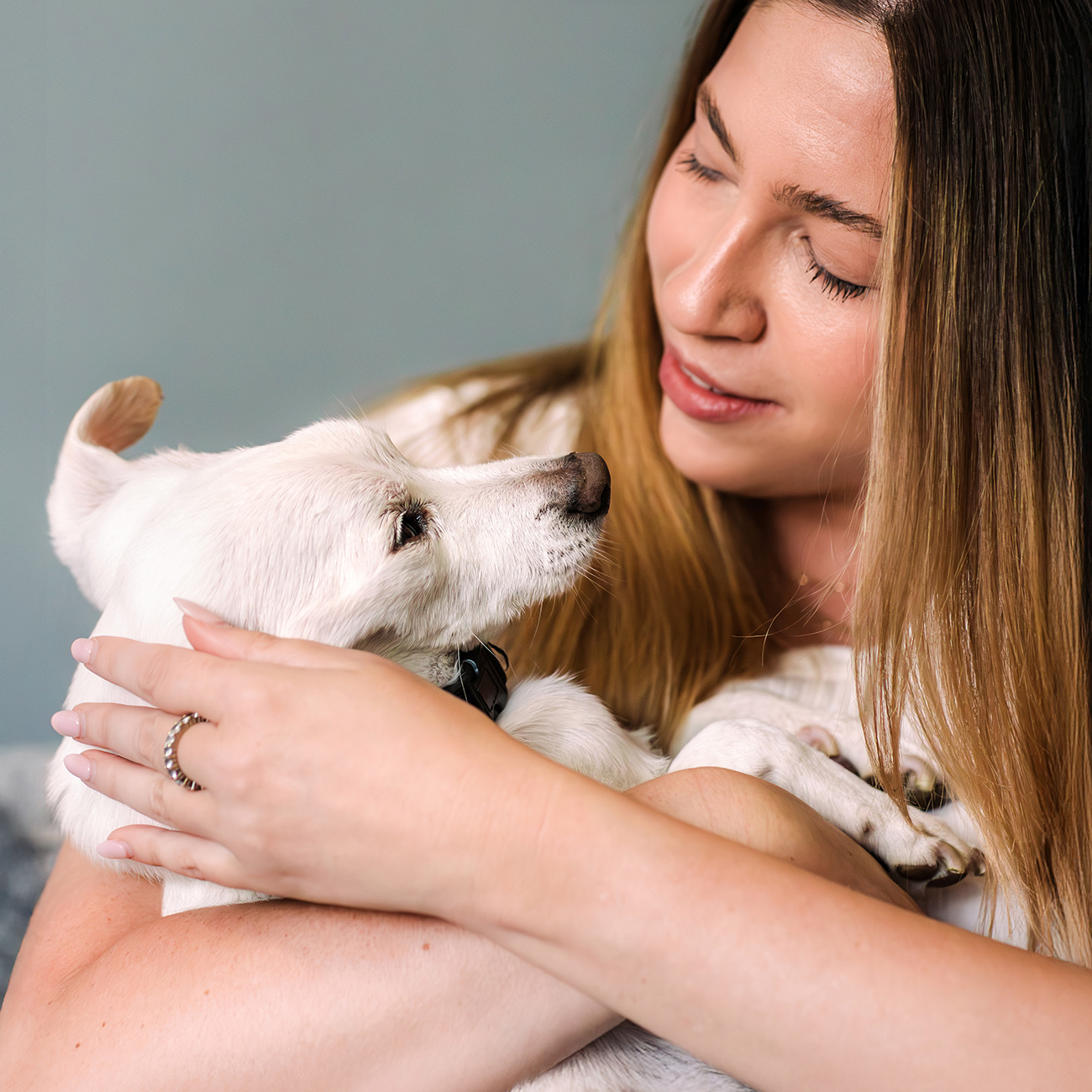 woman holding her small white dog