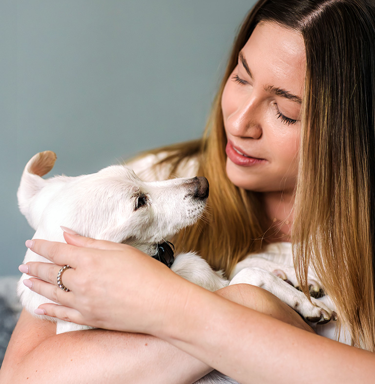 woman holding her white dog in her arms