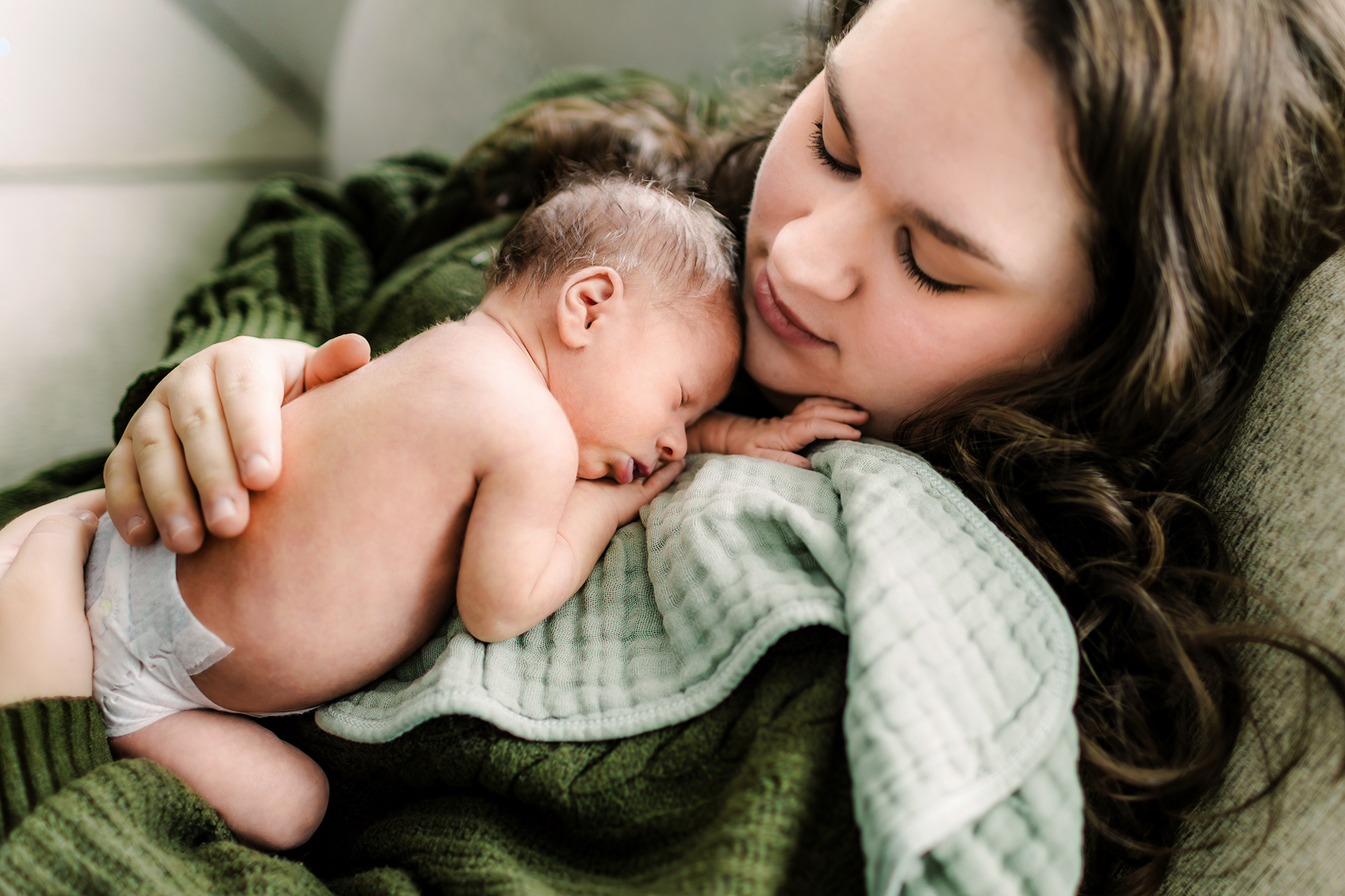 Mom burping a sleeping newborn on her chest
