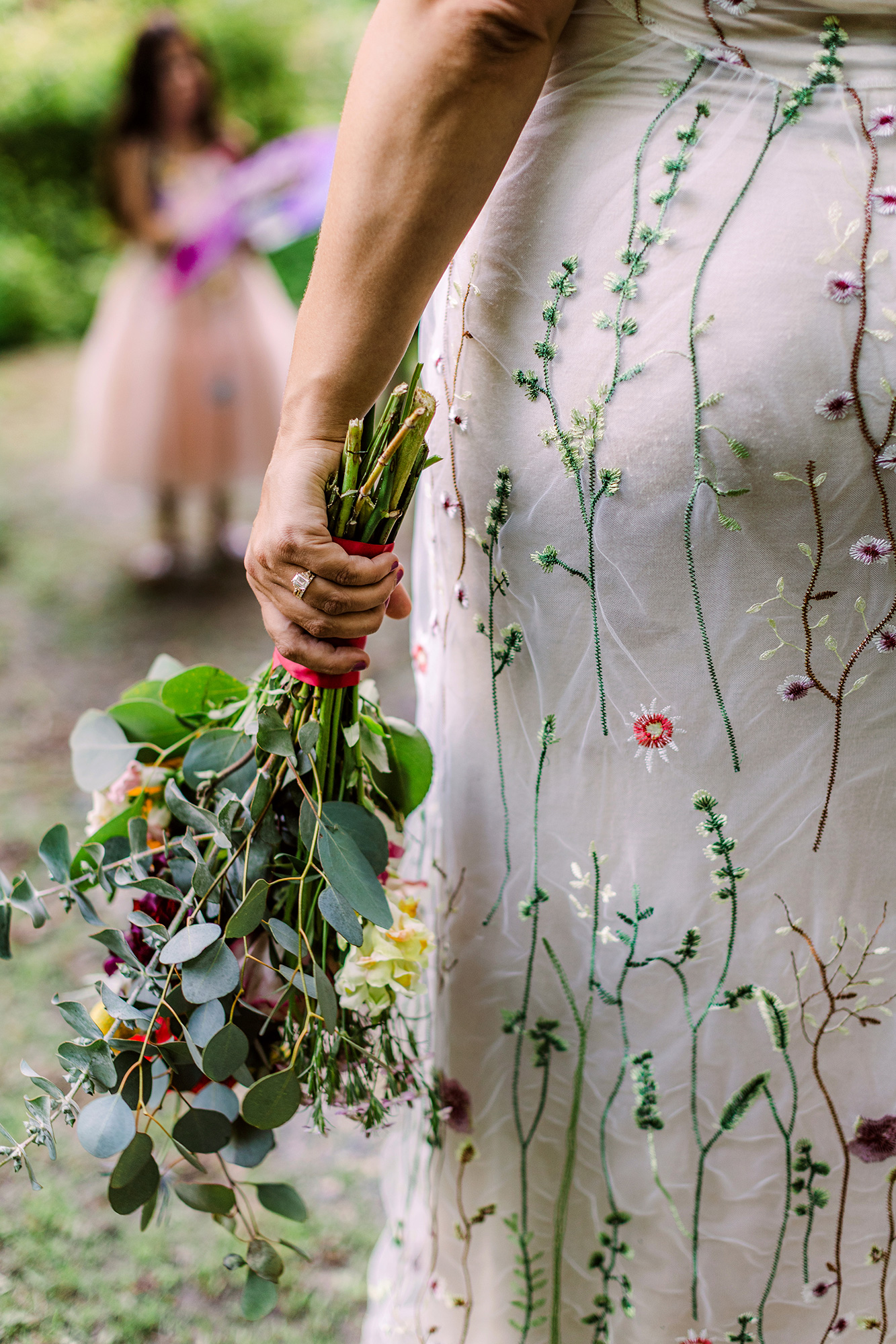 Bride holding her bouquet with the flower girl in the background