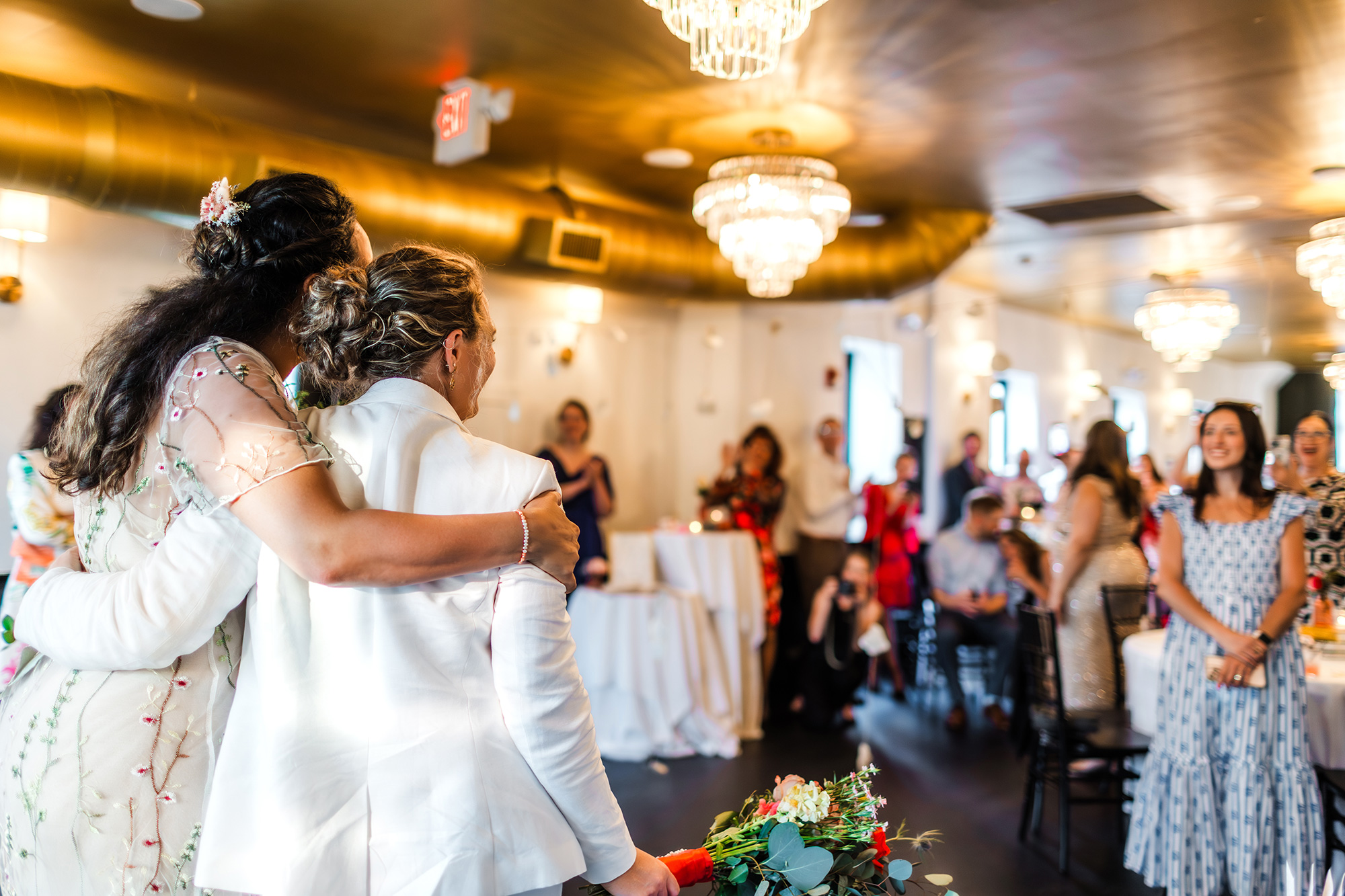 Two brides walking into their wedding reception