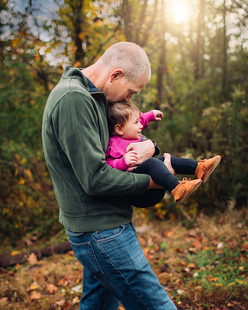 Dad carrying daughter through a fall forest