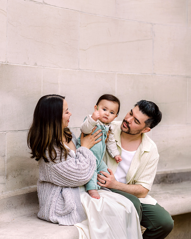 Family of three sitting on stone bench on Kelly Drive
