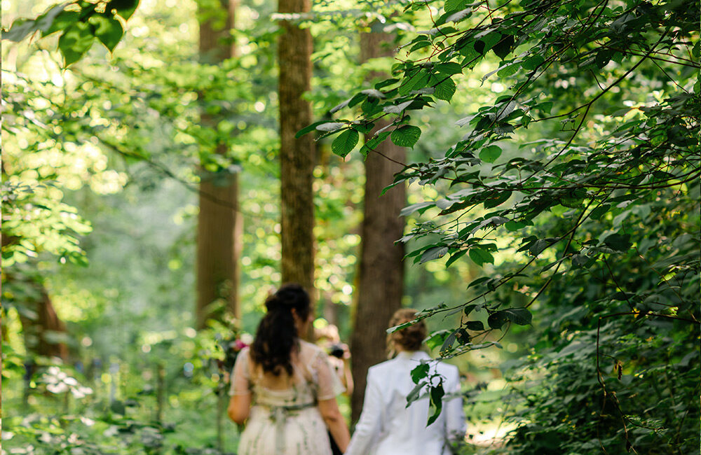 Two brides walking through the woods