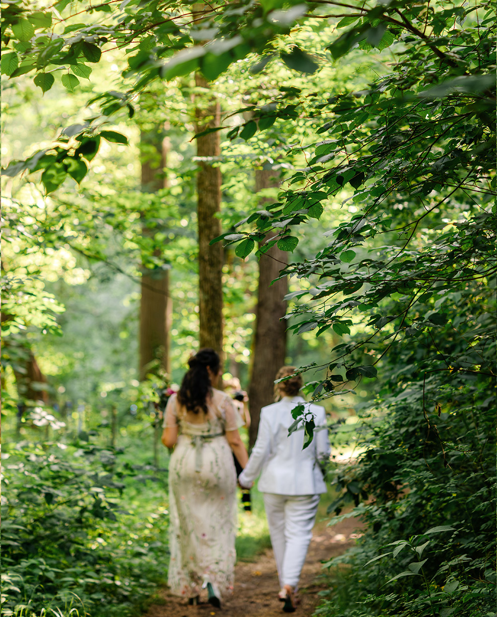 Two brides walking through the woods