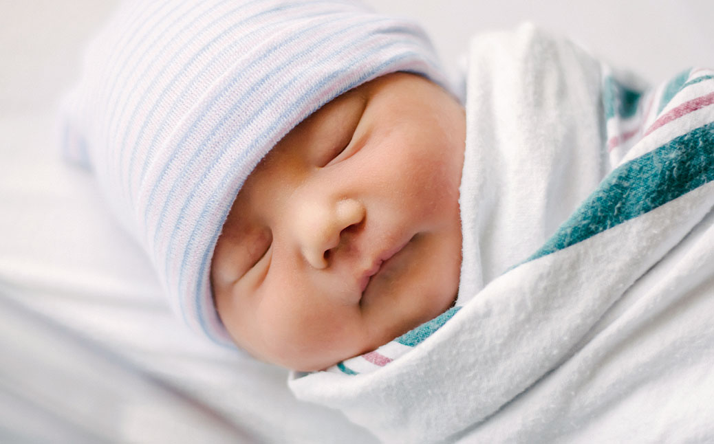 Newborn baby in classic hospital hat