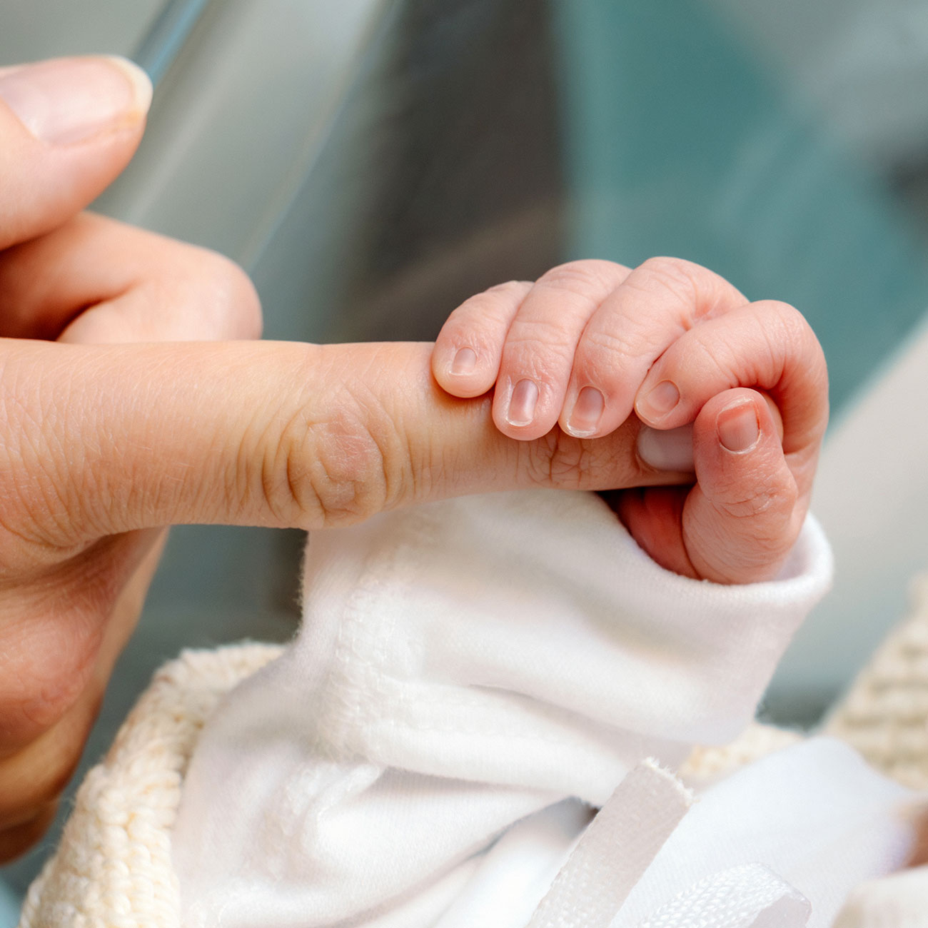 Fresh newborn holding mom's finger