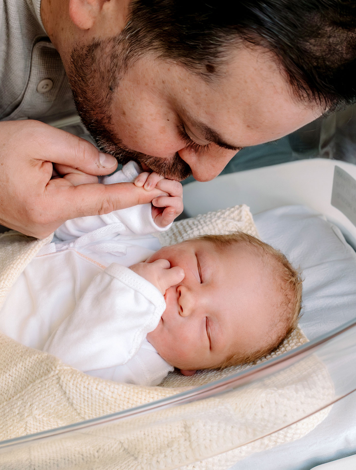 Dad kissing newborn baby's tiny hand, a photo by Evergreen Story