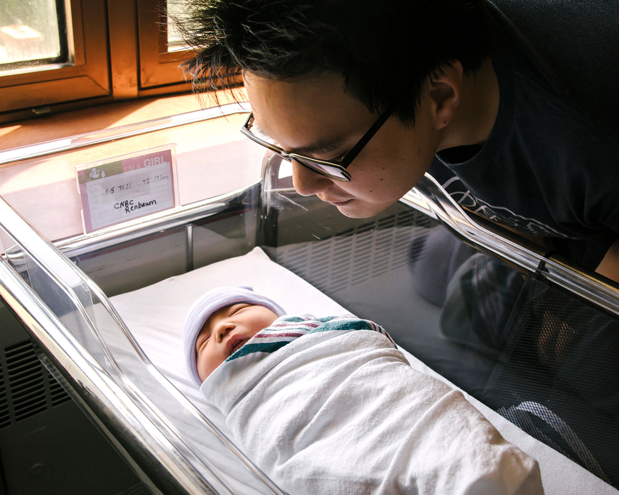 dad peeking into a newborn's bassinet