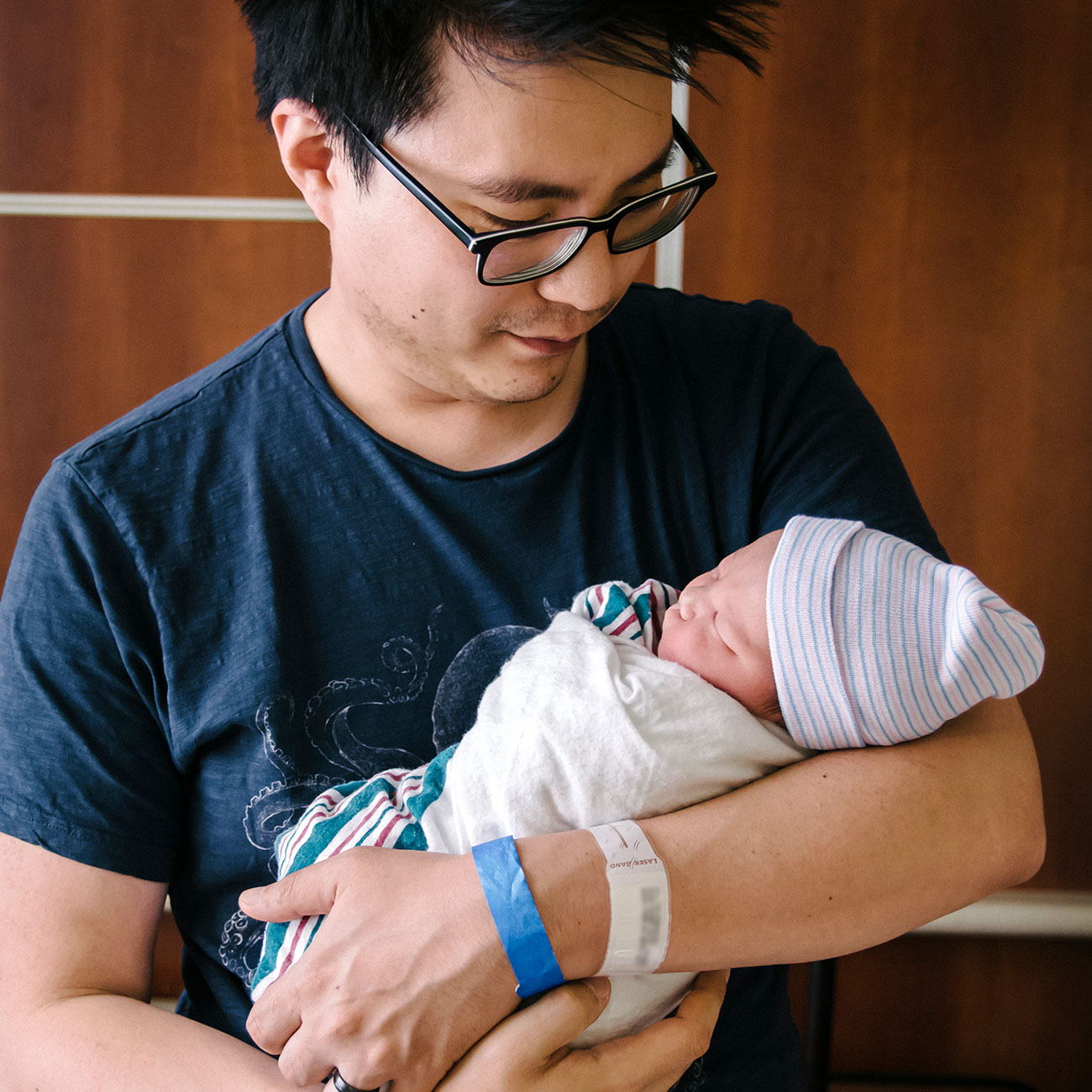 Dad holding a newborn baby in hospital