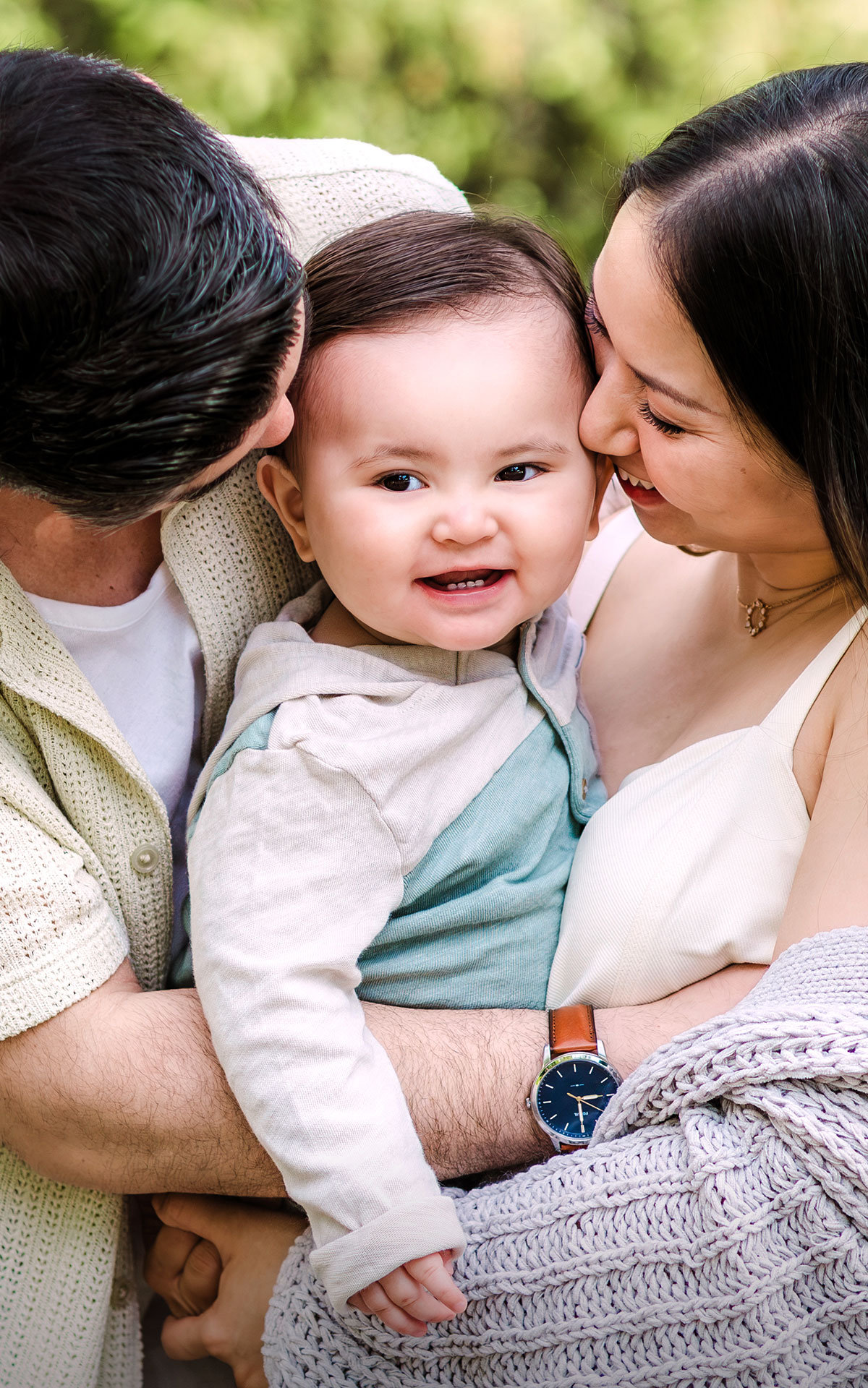 Mom and dad holding a smiling baby between them