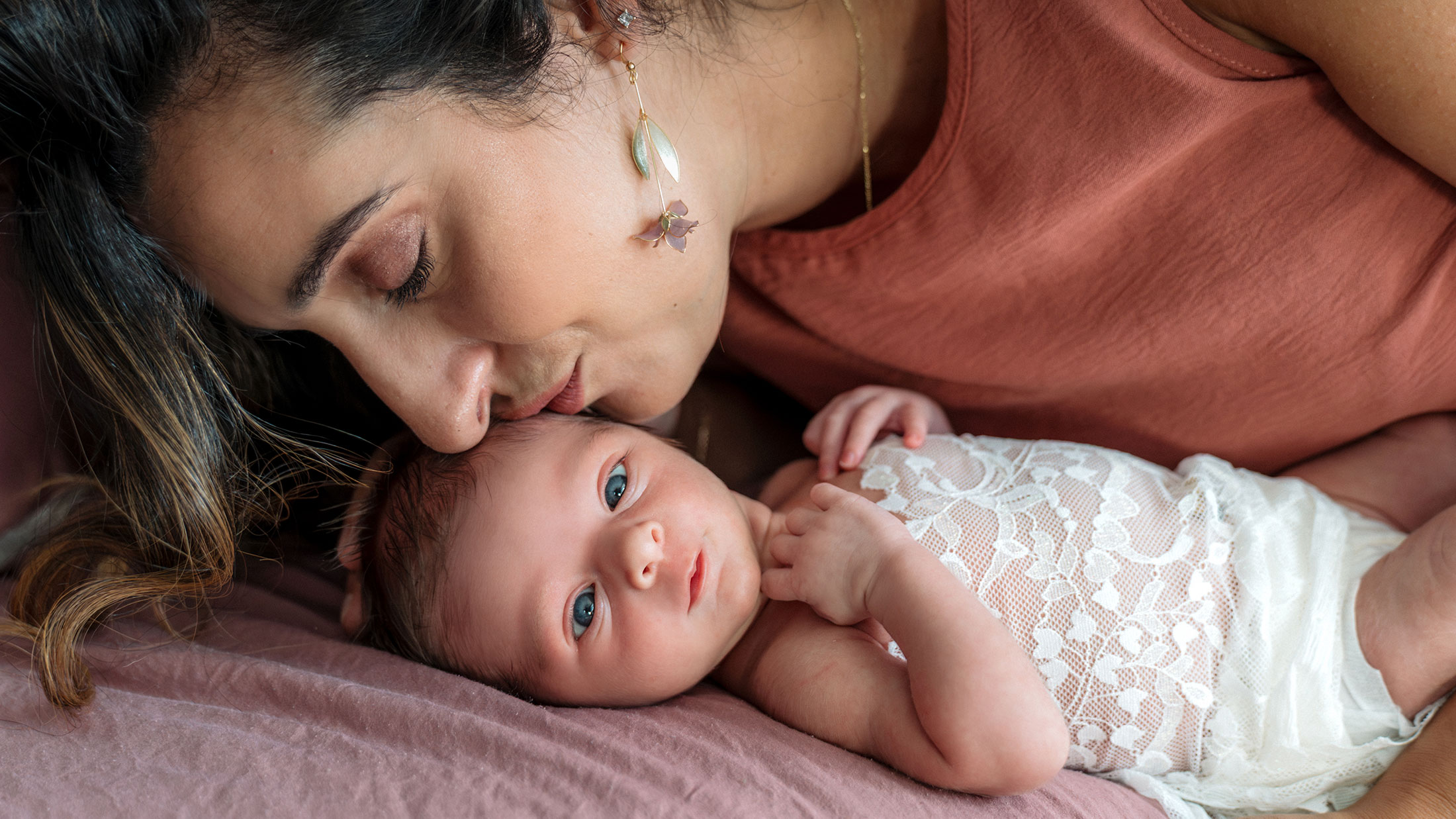 Mother kissing her newborn daughter, a photo by Evergreen Story